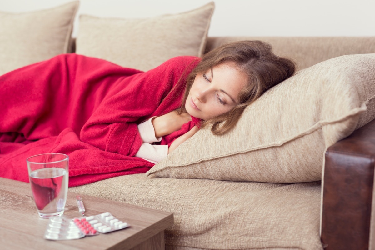 woman lying on couch while sick