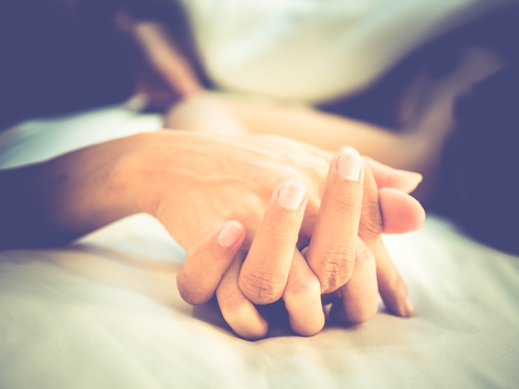 this couple holding hands on a bed implies that they're having sex!