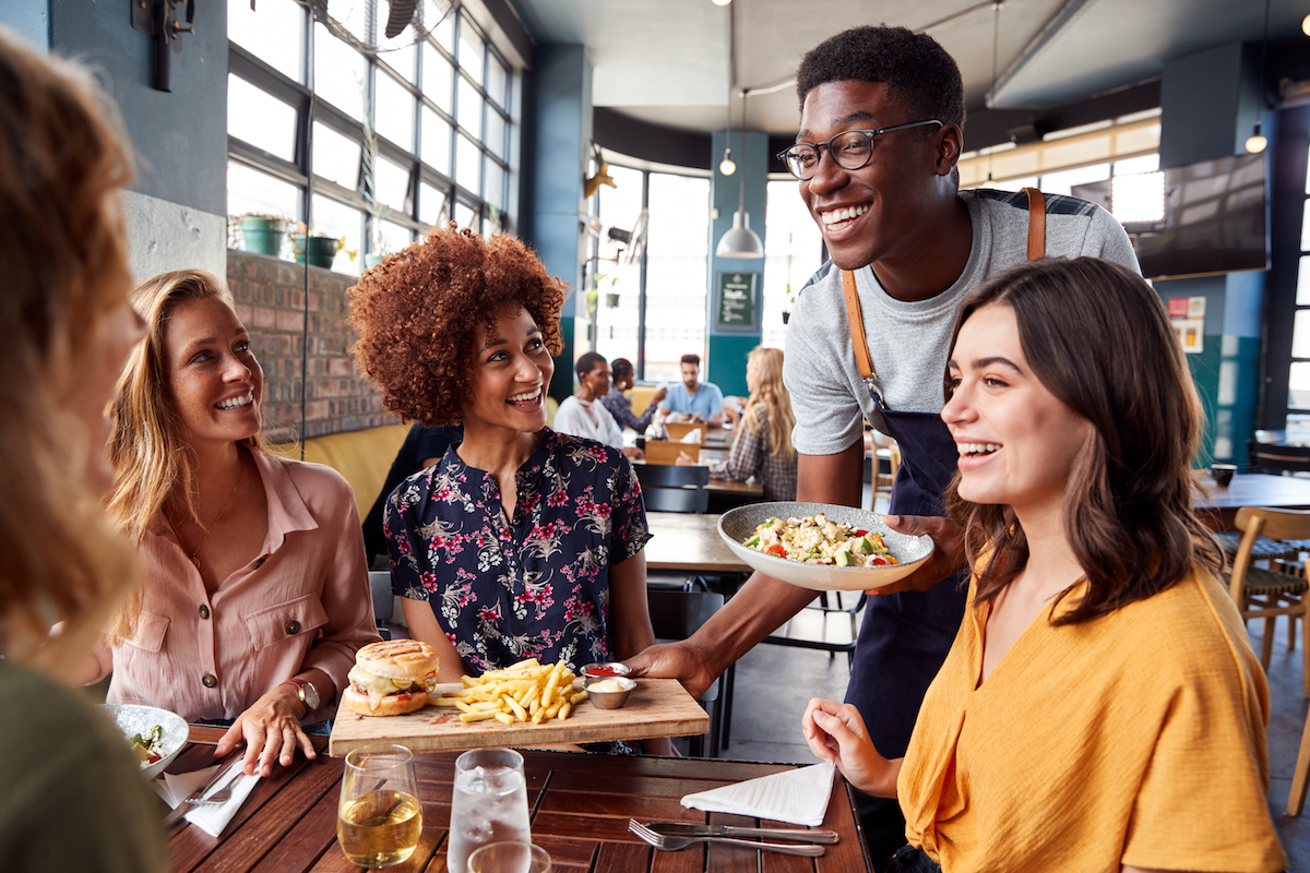 Group of friends smiling at waiter in restaurant