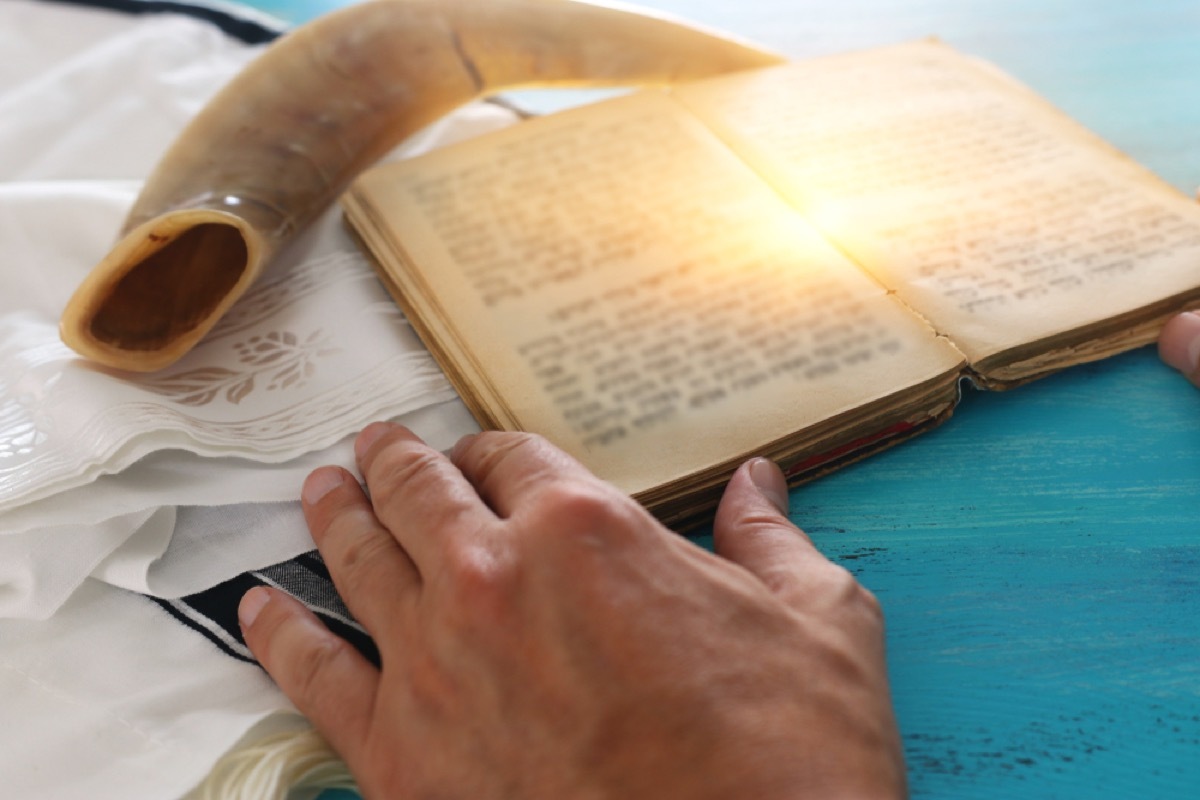 man reading torah with tallit and shofar behind it