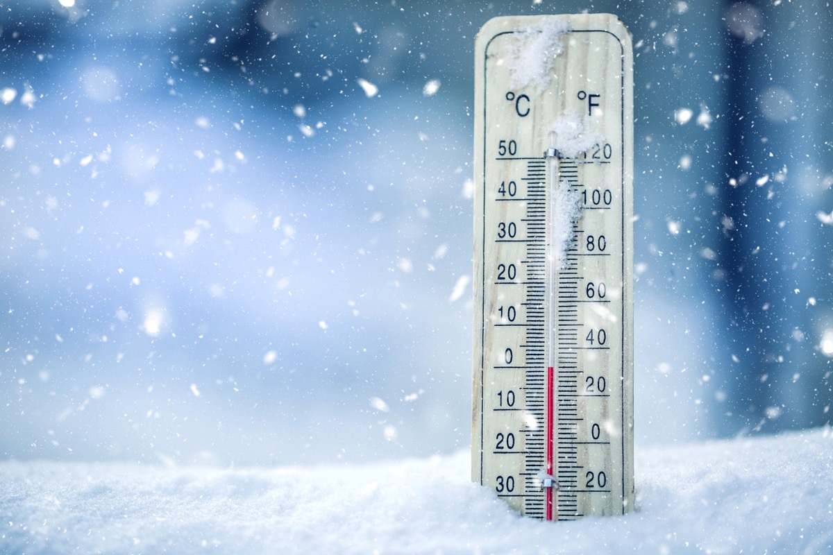 Thermometer on snow shows low temperatures - zero. Low temperatures in degrees Celsius and fahrenheit. Cold winter weather - zero celsius thirty two farenheit.