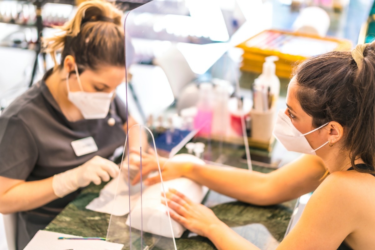 woman paying with credit card at salon wearing face mask