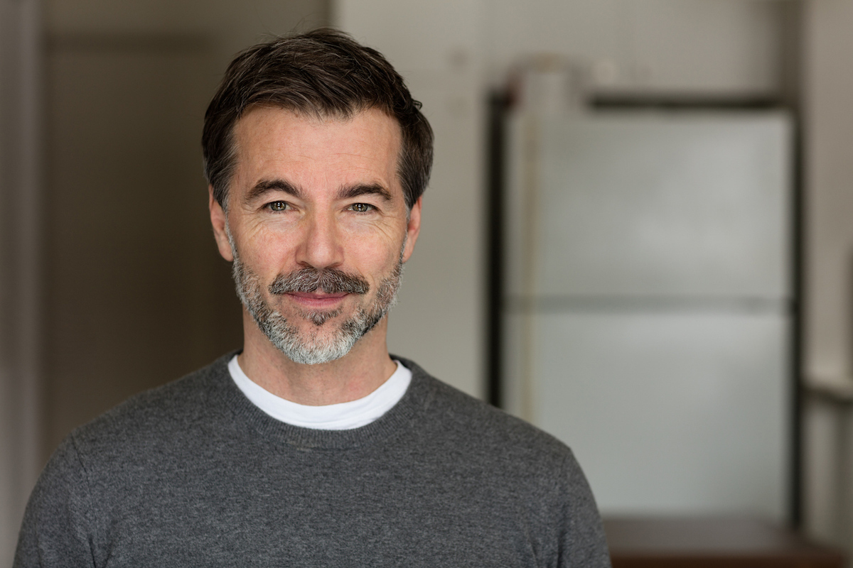 Portrait of a middle-aged man with a salt-and-pepper beard and mustache wearing a dark-gray sweater