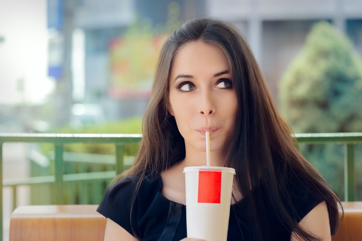 Woman drinking soda trough a straw.