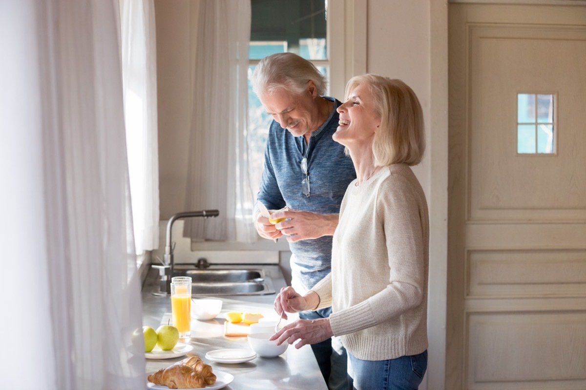 Older couple talking and laughing in kitchen