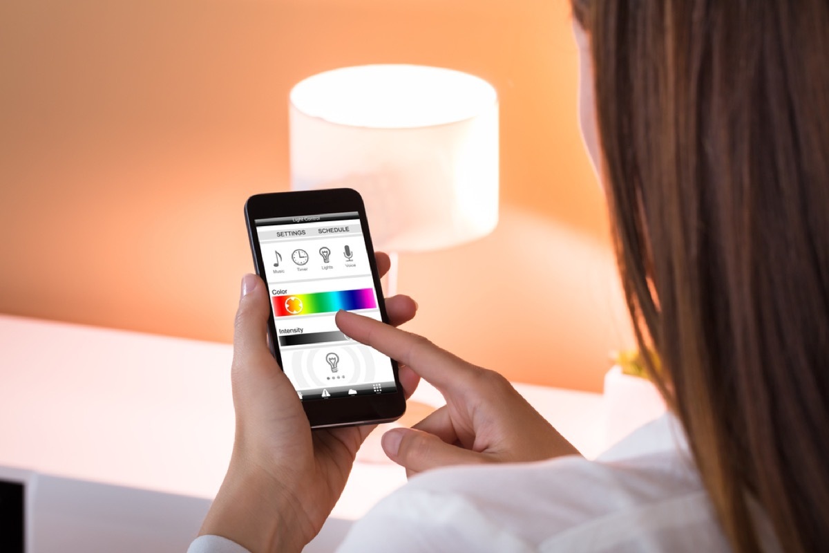 woman using app to dim lights on smartphone