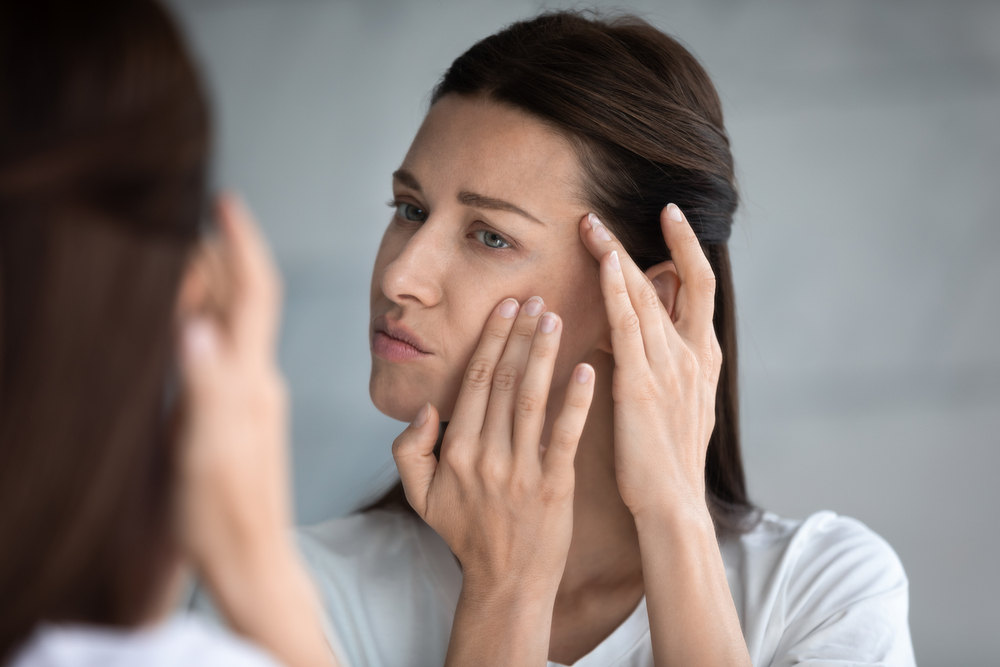 A young woman checking her face in the mirror