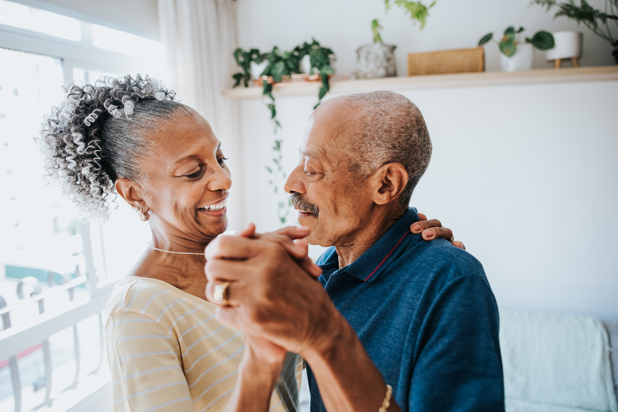 A senior couple smiling and dancing with each other