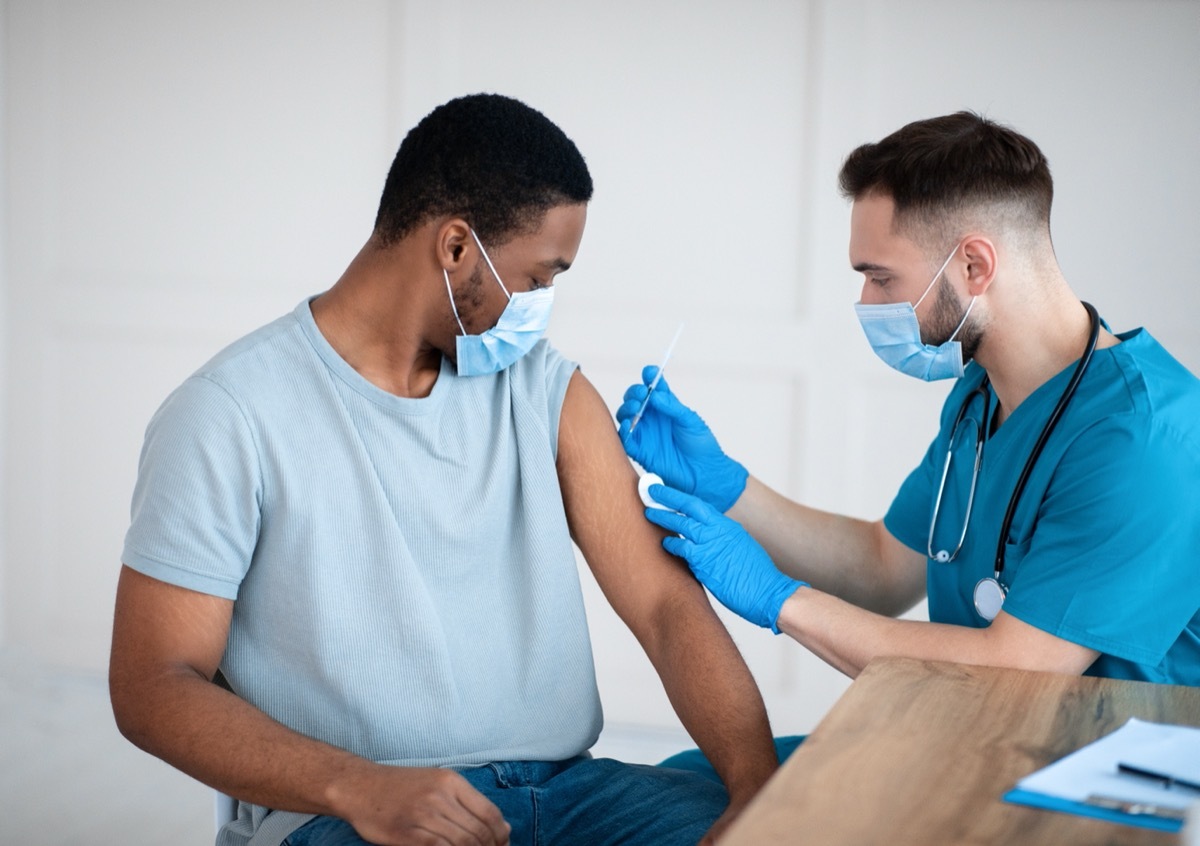 doctor giving young man a covid vaccine