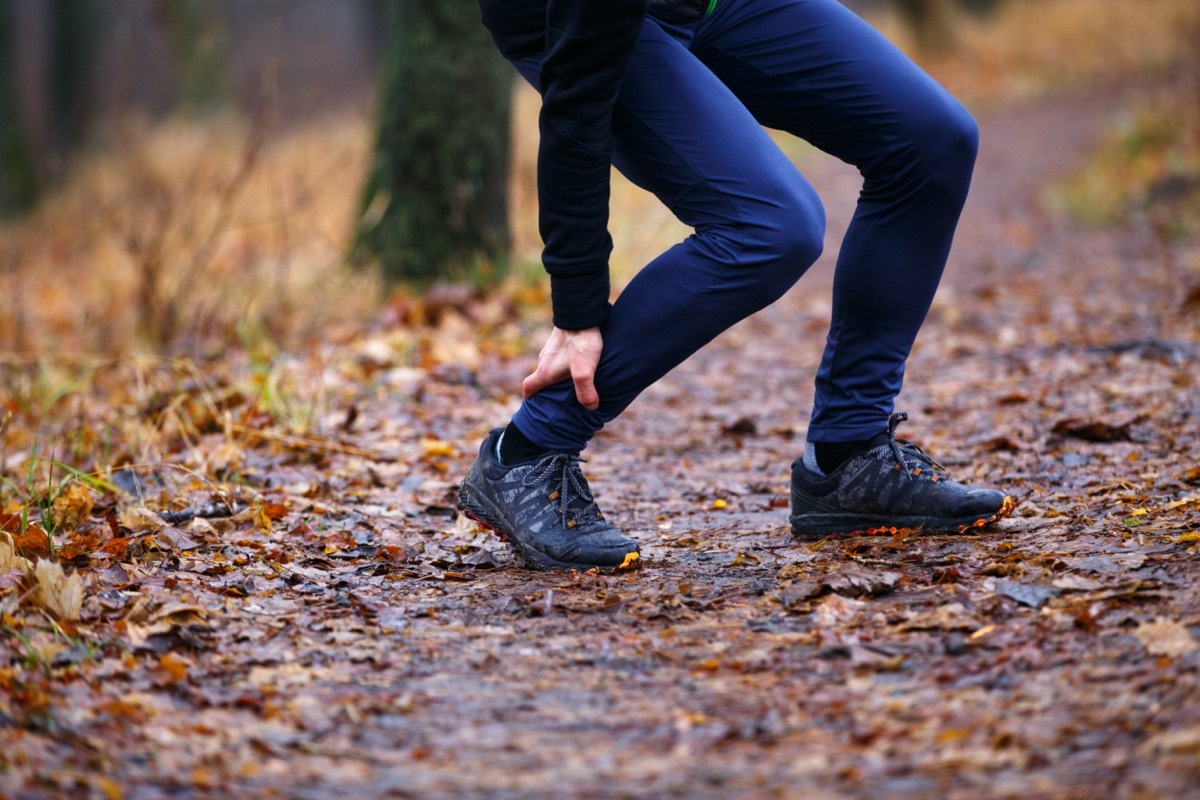 Male runner touching cramped calf at morning jogging.