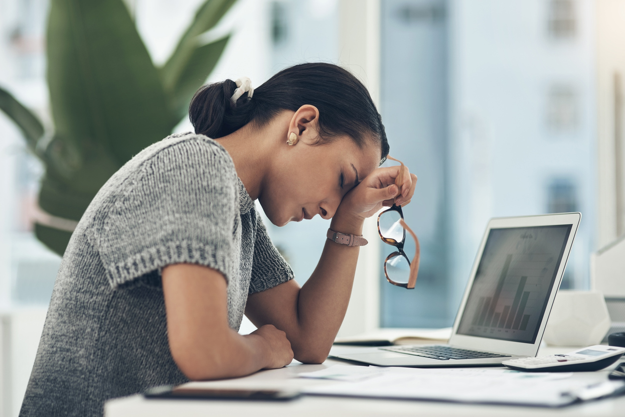 Woman at desk feeling fatigued.