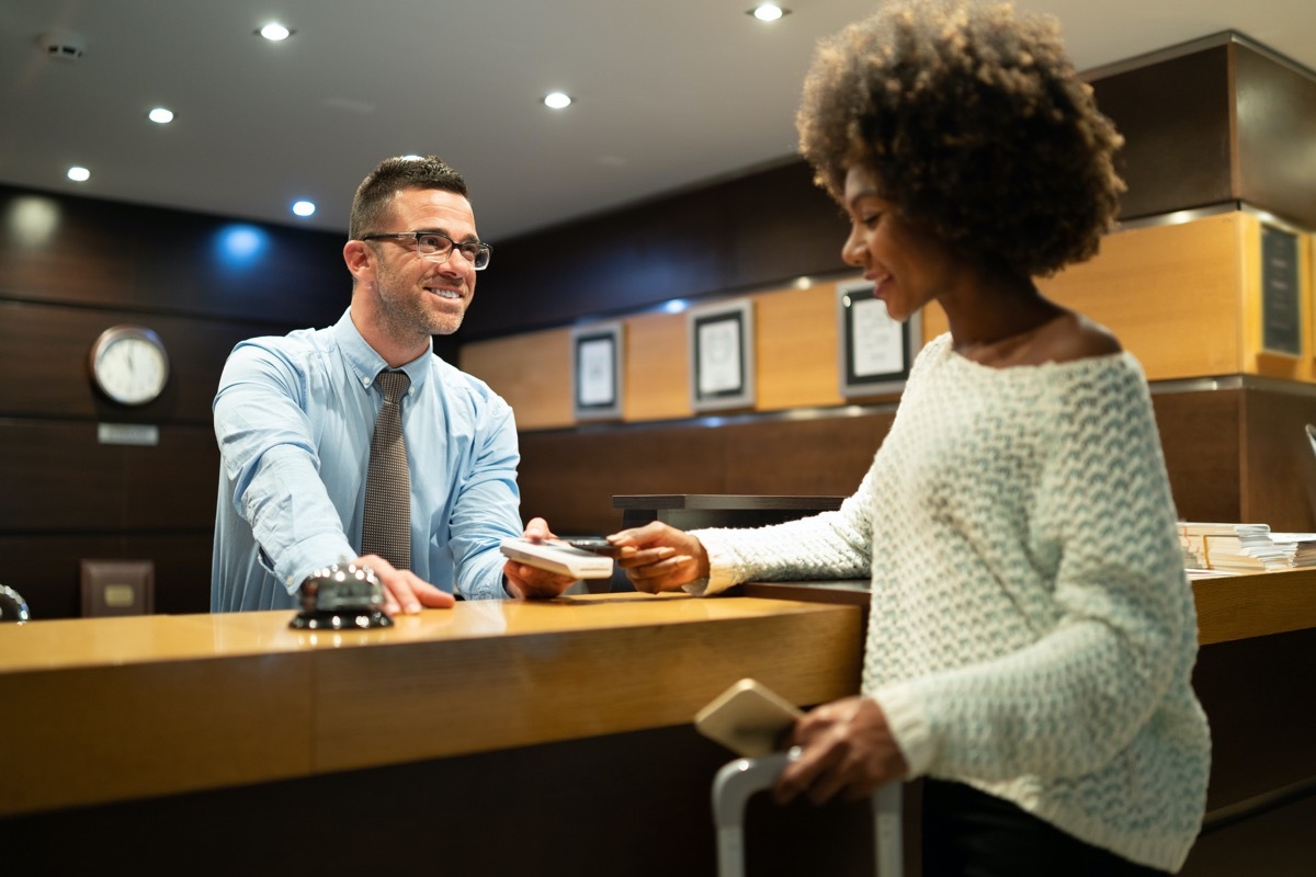 Businesswoman at reception, paying for hotel room.