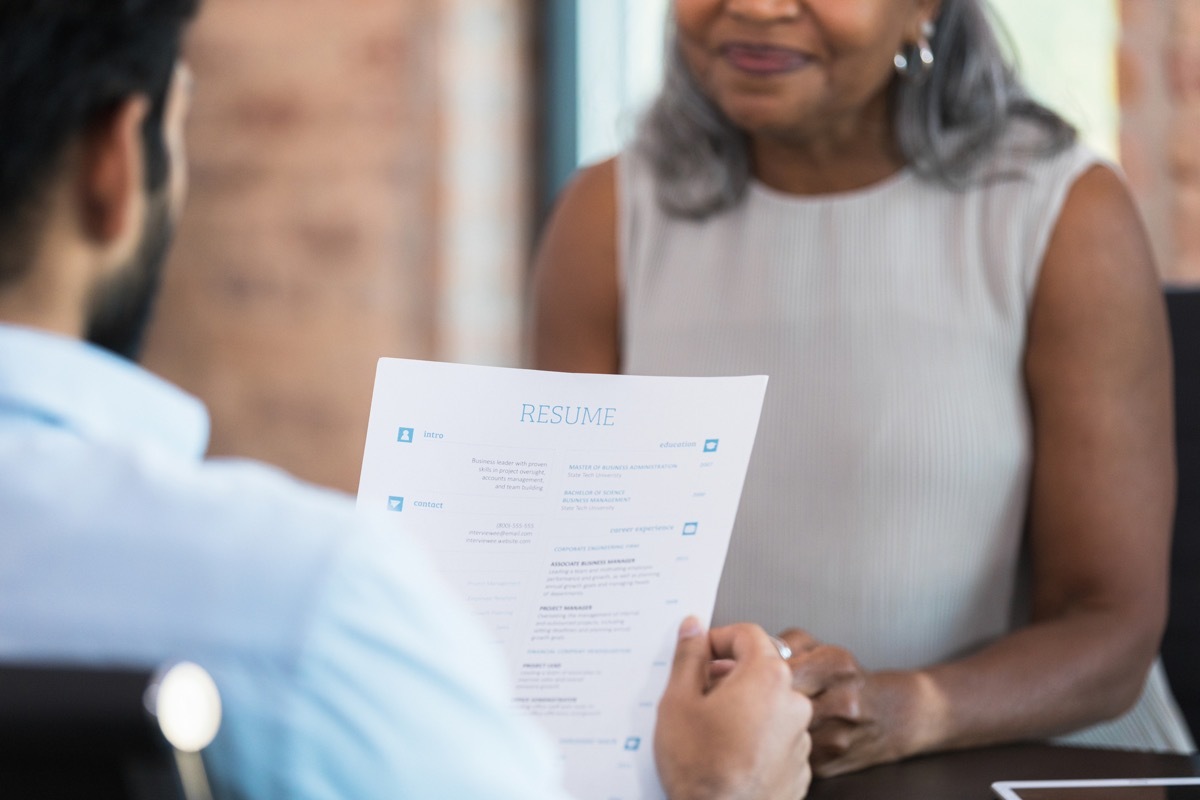 A businessman reads a resume during a job interview with a woman