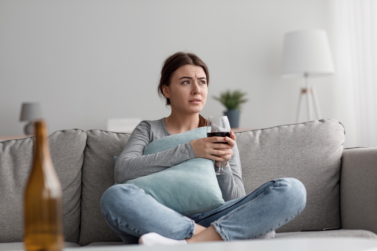 Sad frustrated tired caucasian pretty millennial woman with glass of wine suffering from depression, loneliness and stress at home, empty space. Bad relationships, problems, addiction and crisis