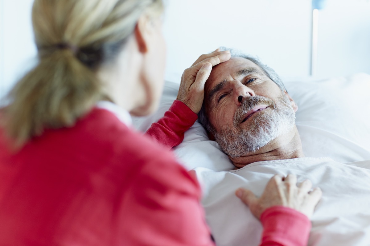 Woman caressing ill man in hospital ward after heart attack