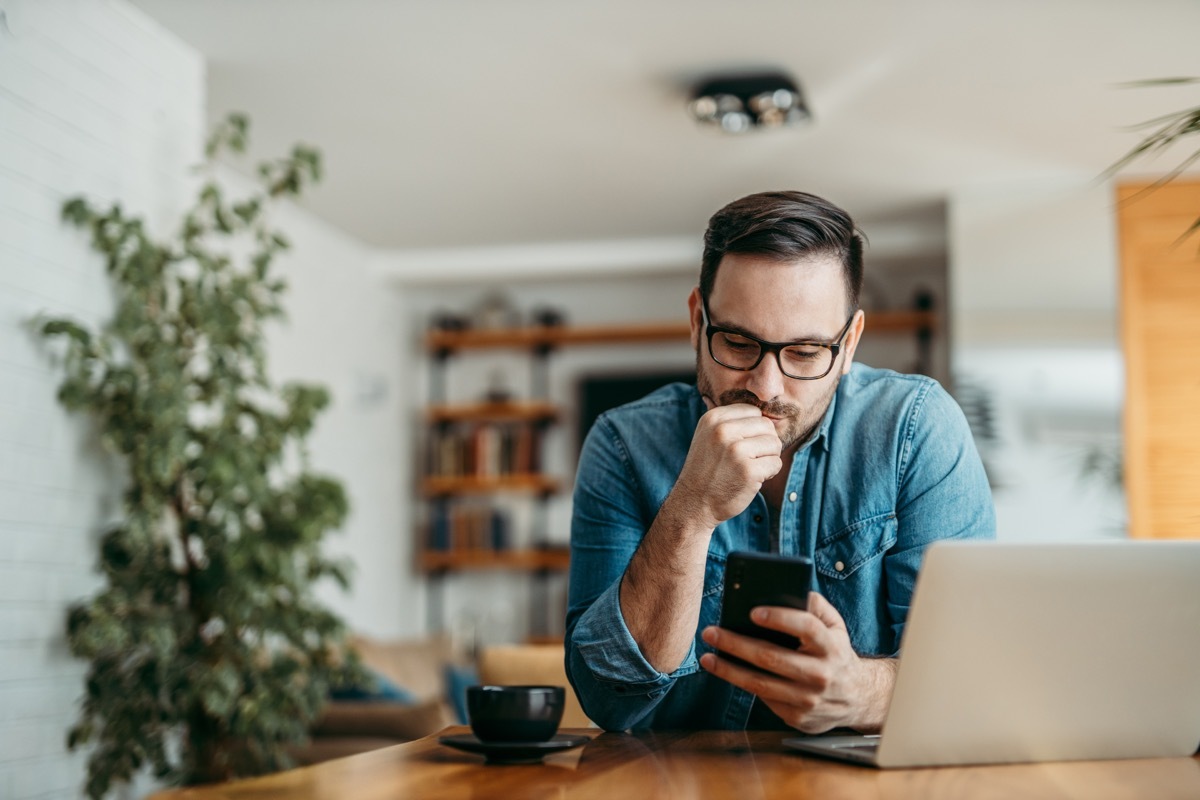 Man on his laptop and phone sitting in his office.