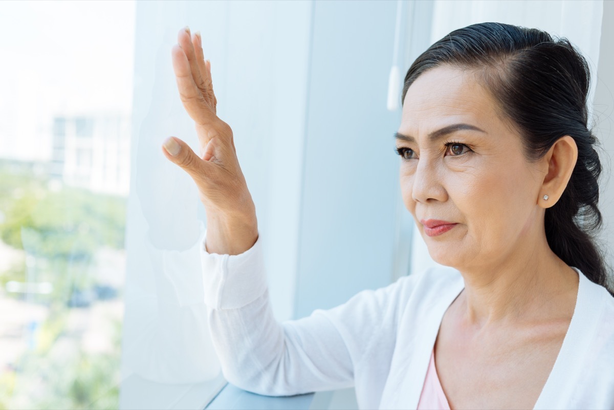 Contemplating Asian aged woman looking out of the window