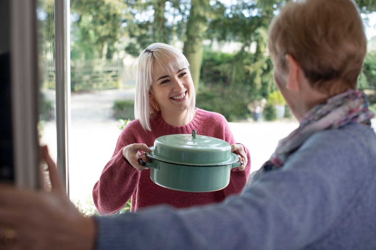 woman bringing a pot to her neighbor