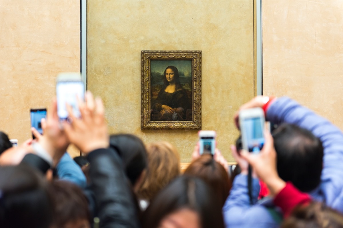 people trying to take a picture of the mona lisa