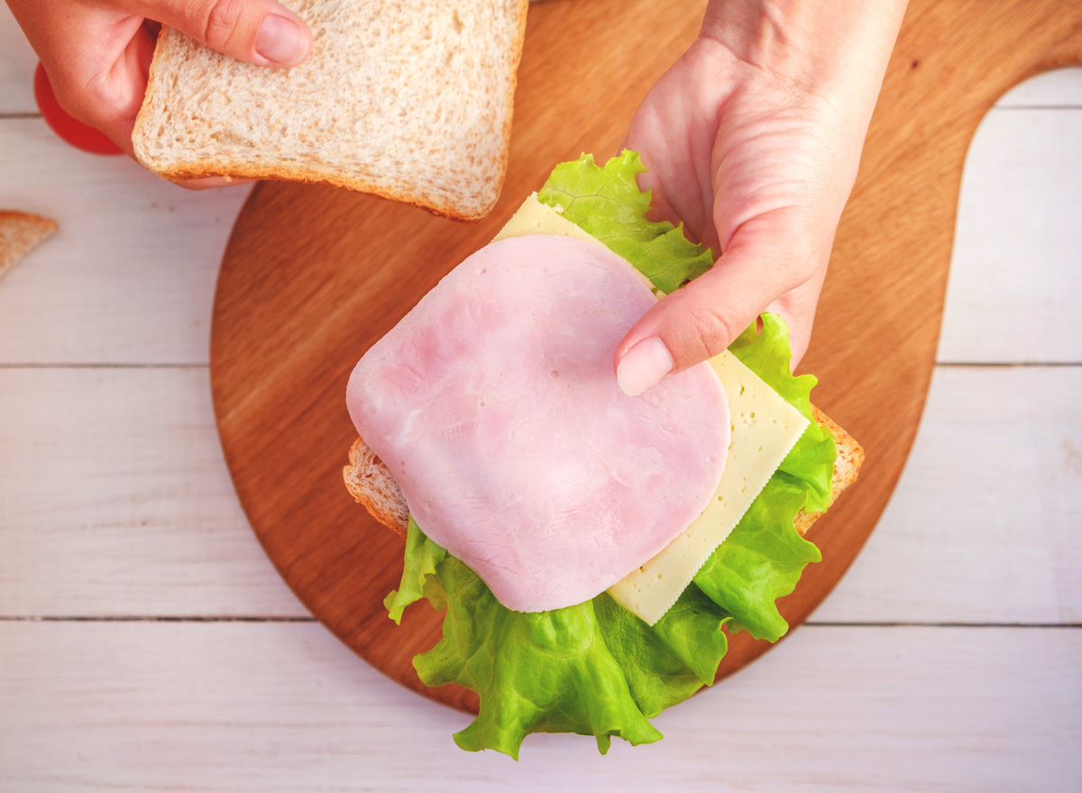 woman making sandwich bread lettuce cheese deli meat for lunch