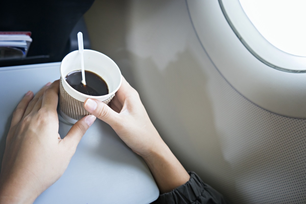 female's hands holding coffee cup on plane