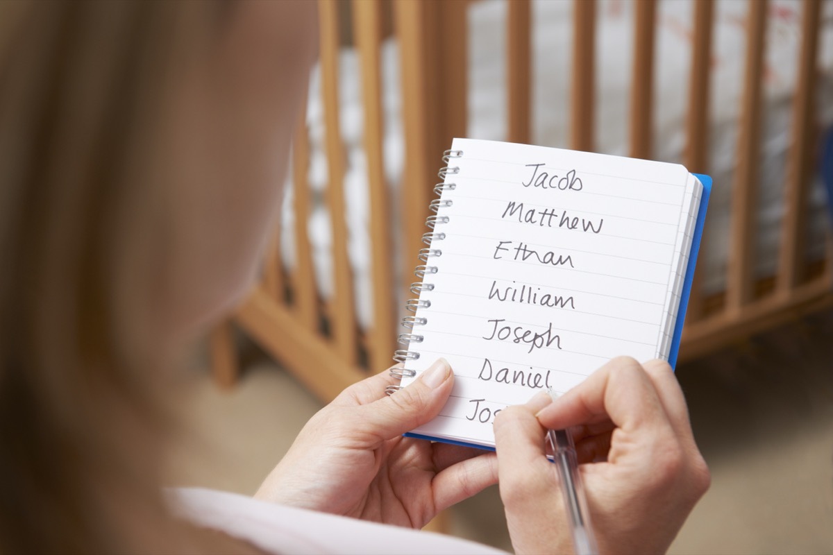 Woman Writing Possible Names For Baby Boy In Nursery