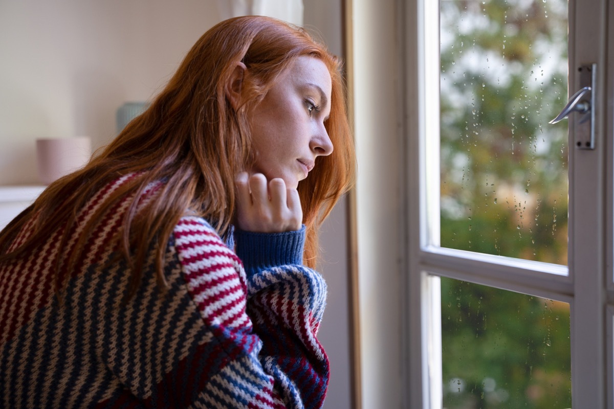 Lonely-looking young woman looking out window