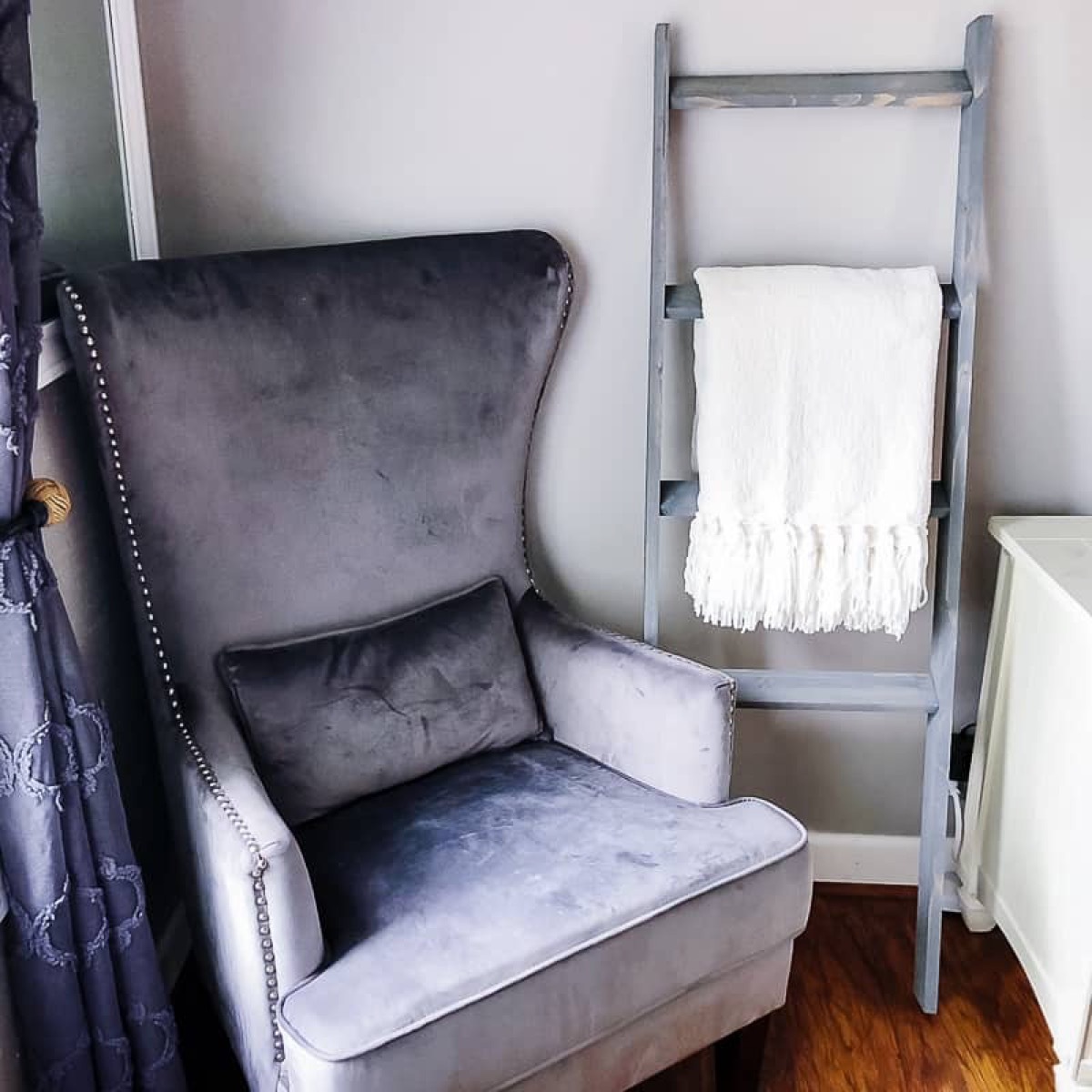 gray chair next to ladder with blanket on it