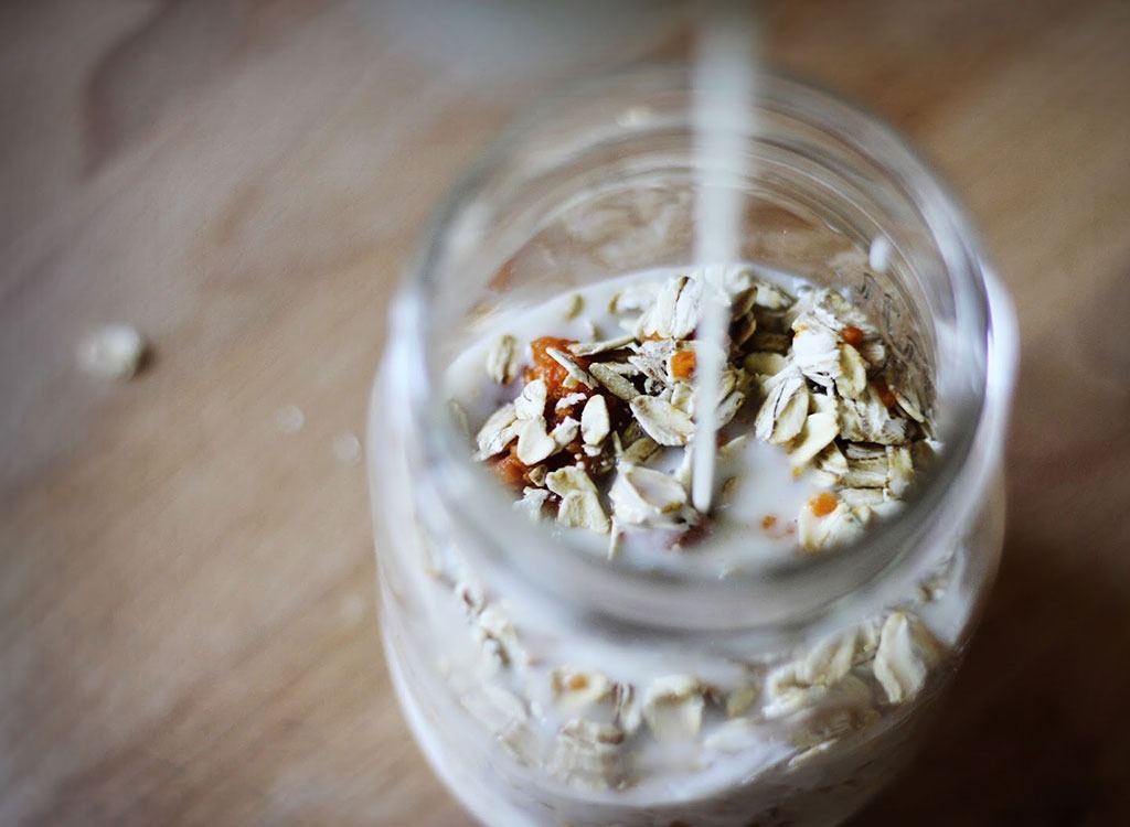 pouring milk into a mason jar of oats