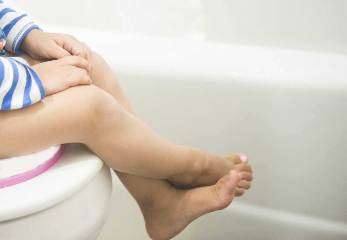 A potty training toddler sitting on a comode