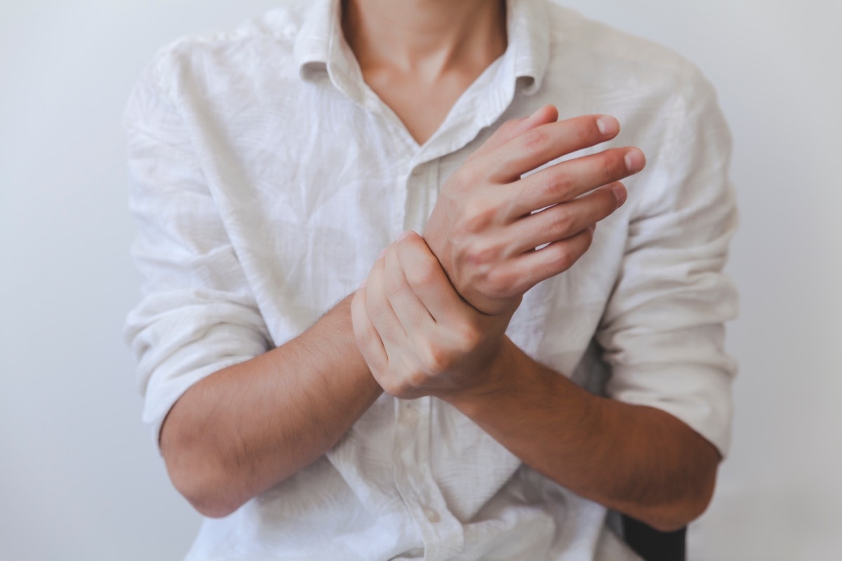 male arms holding his painful wrist