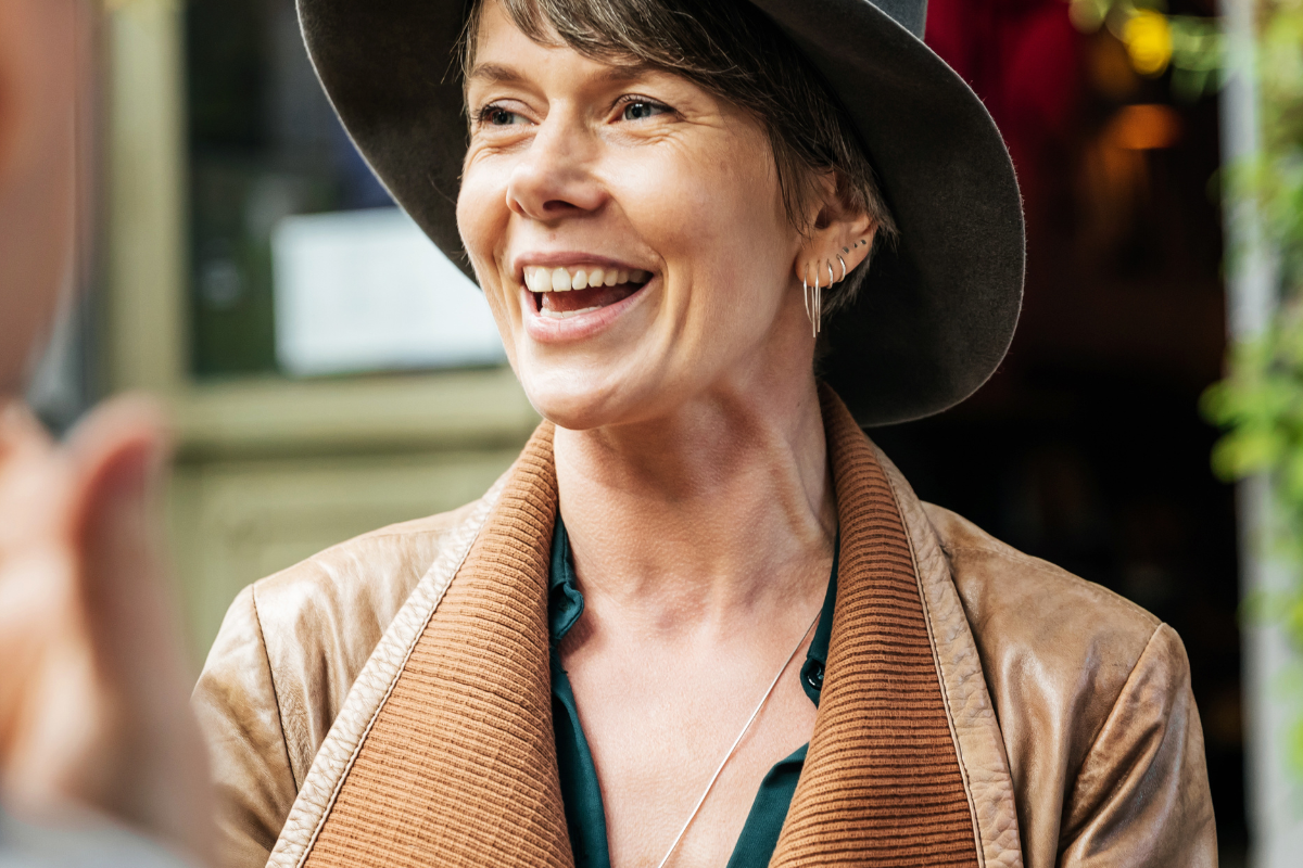 woman laughing in leather jacket hat