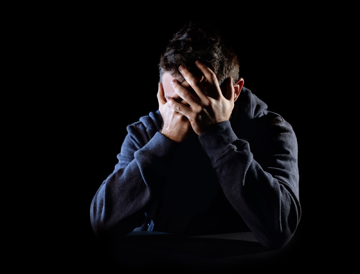 man covering his face in the dark