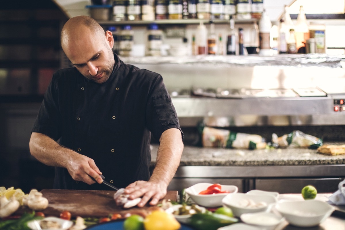 Young Chef Preparing Meal In Kitchen Restaurant