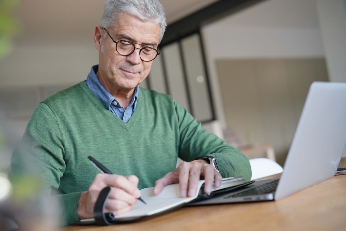 Older man writing down his thoughts in a journal or notebook