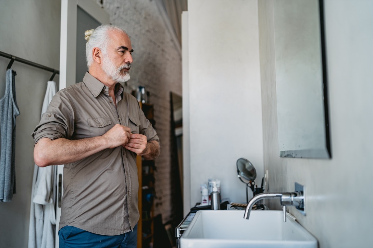 Senior handsome man dressing up in bathroom.