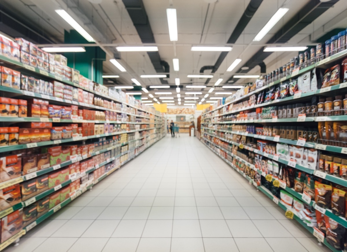 blurred, long, and empty aisle of supermarket with colorful shelves