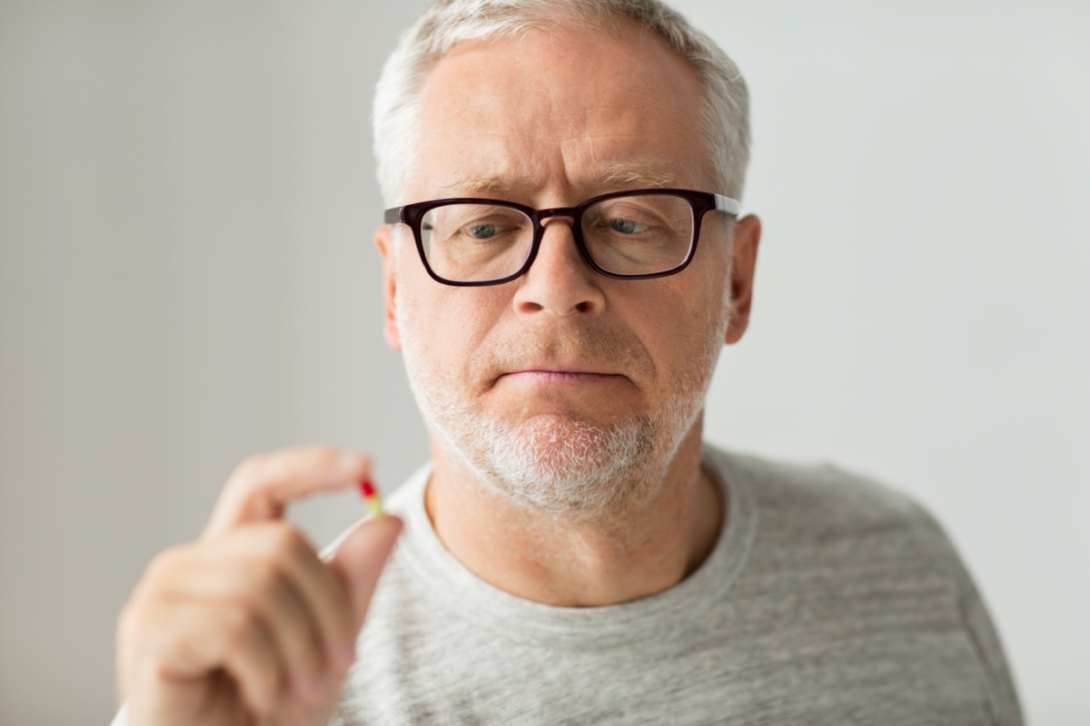 senior man taking medicine pill at home