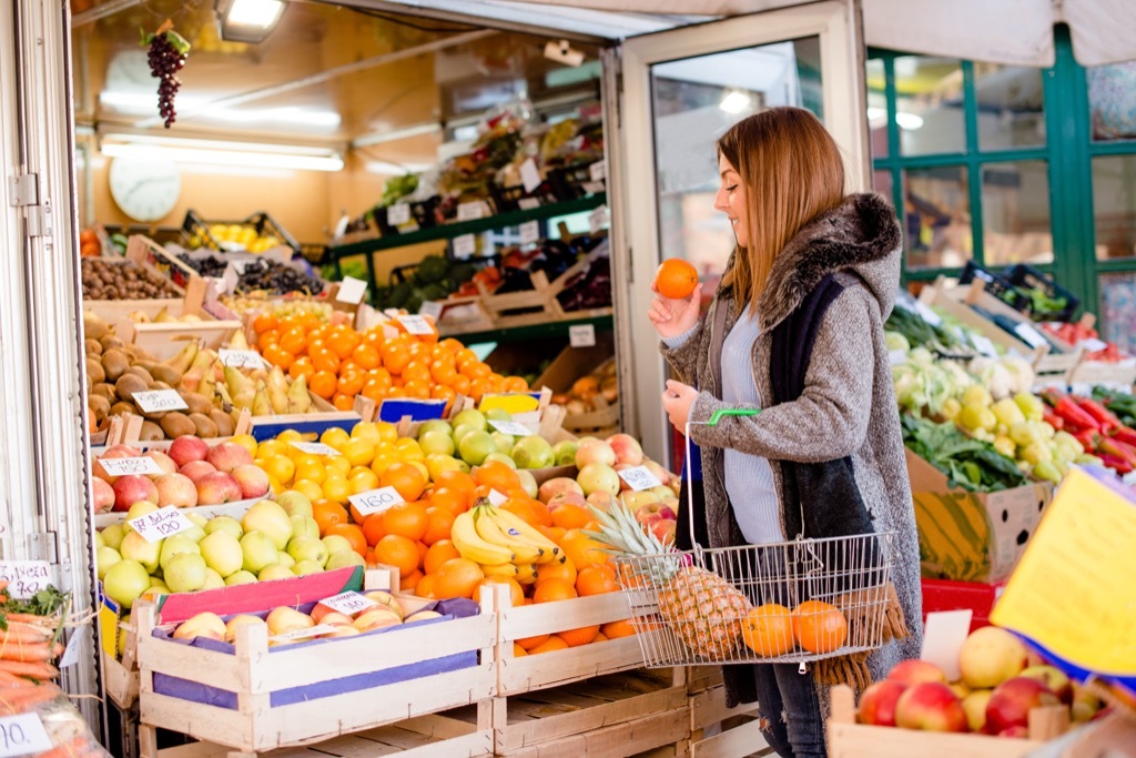 woman at grocery store buying fruit {Never Buy at Costco}