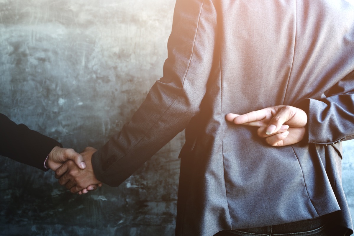 shady business man crossing his fingers behind his back while shaking hands, indicating that he is a liar or lying, ancient rome facts