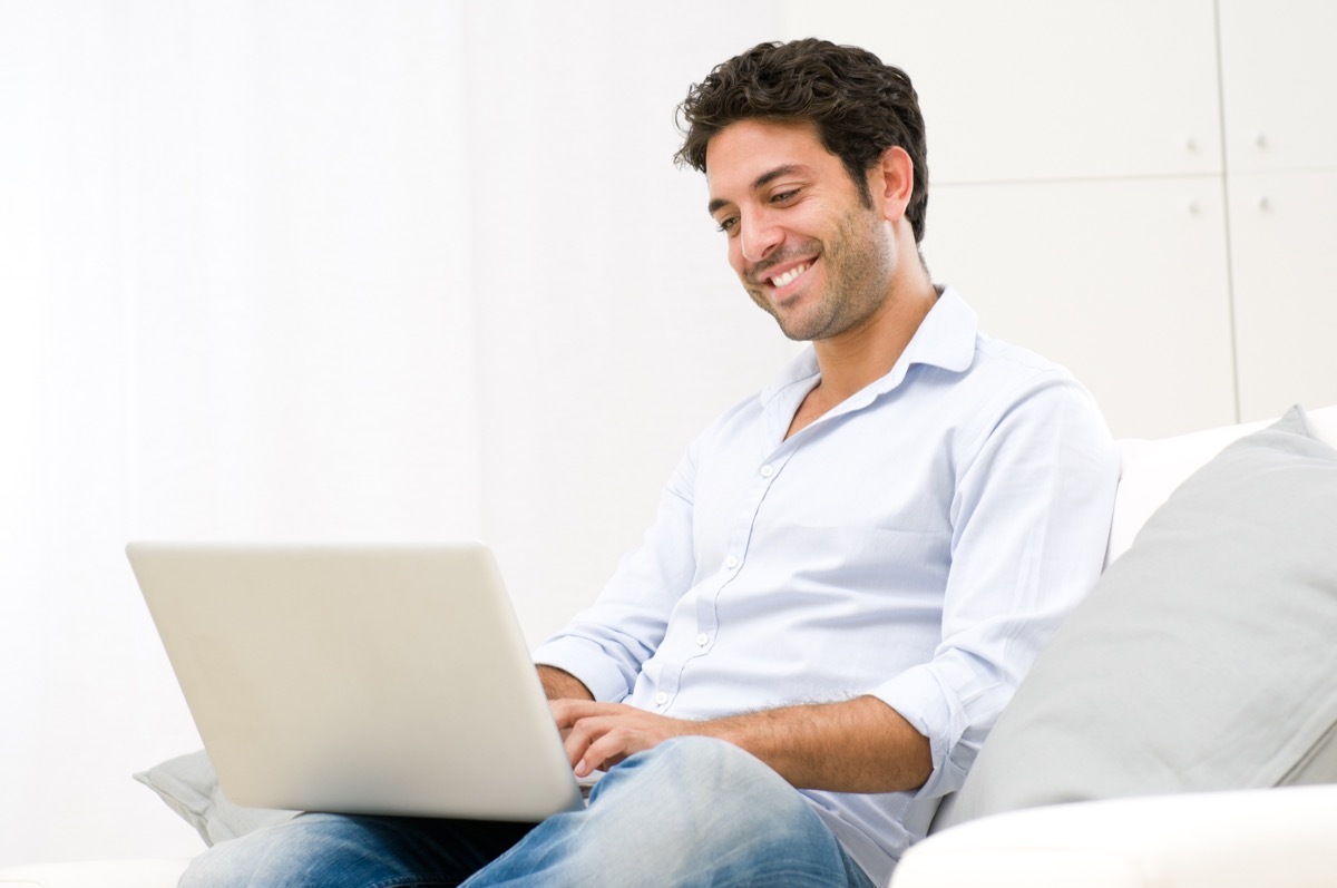 Man happily doing work on his laptop at home