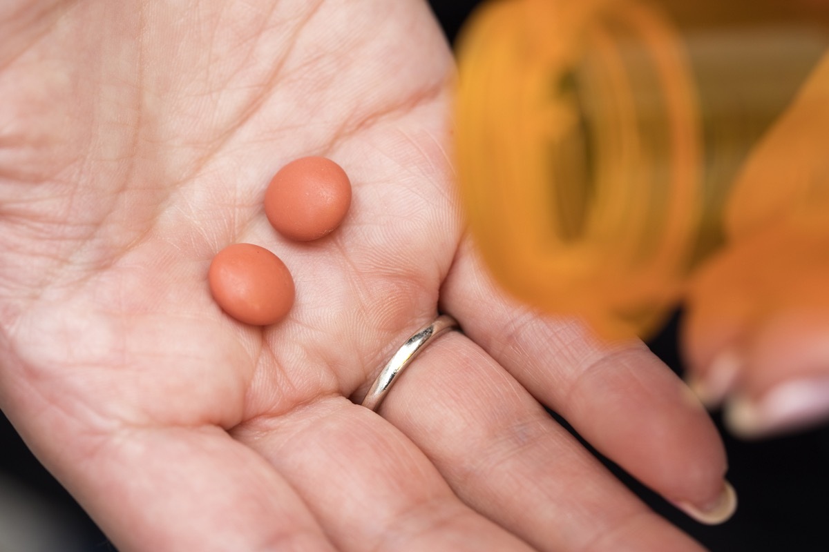 Two Ibuprofen pills spilling out of bottle.