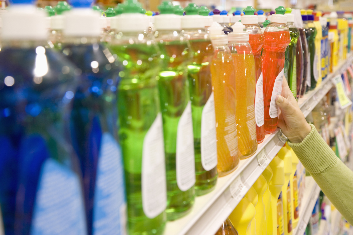 Woman selecting dishwashing liquid product in supermarket