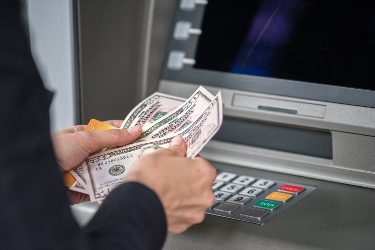 Man counting money in front of cashpoint.