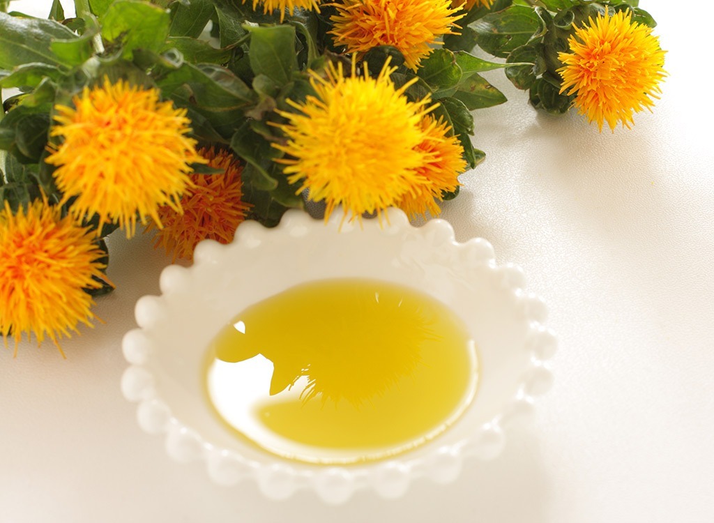 bowl of safflower oil next to plant in white dish