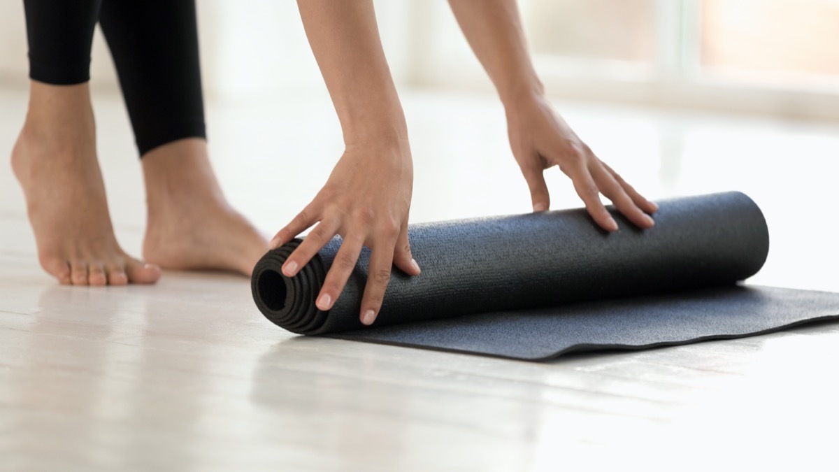 Woman wearing black leggings finished or starting workout rolling mat