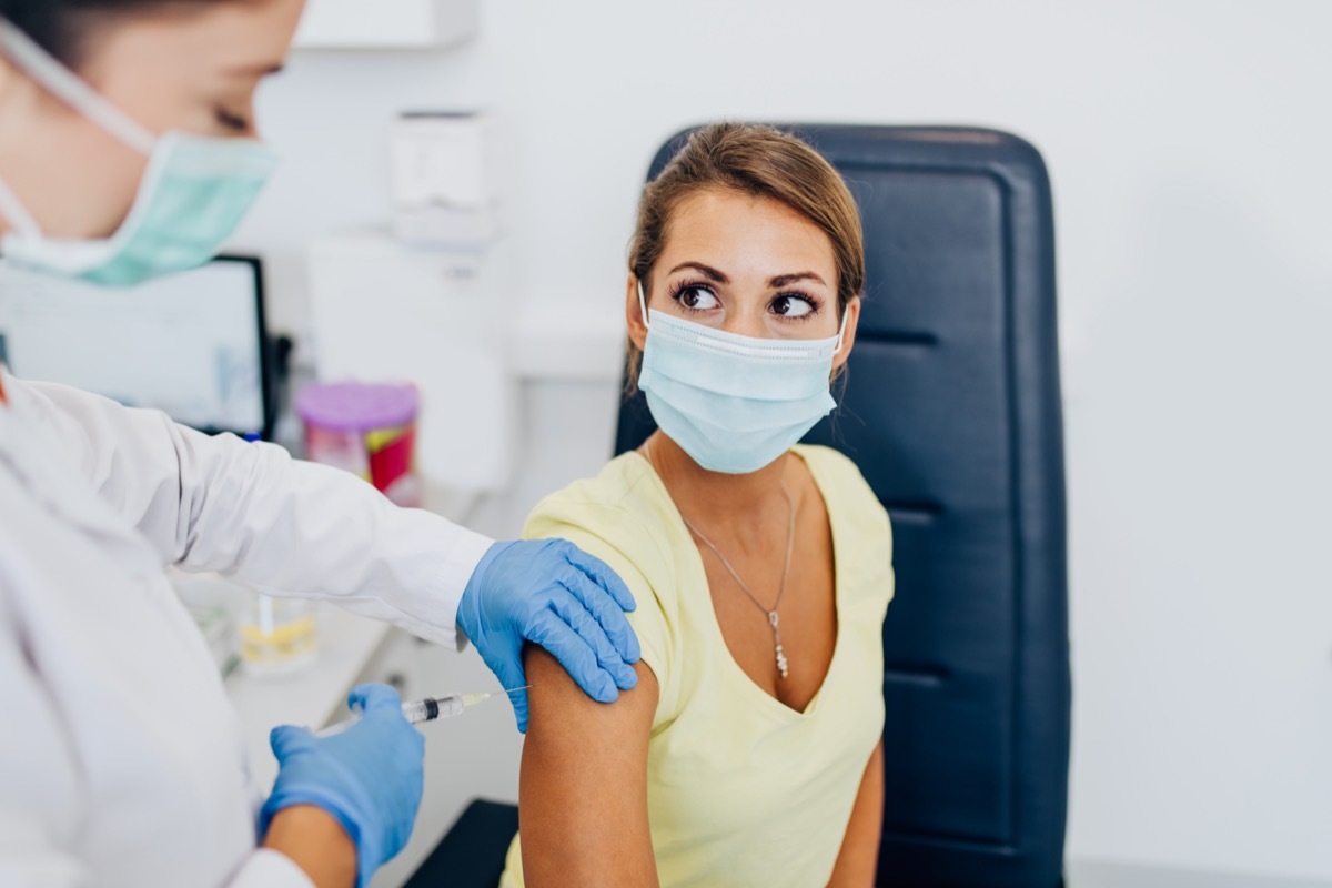 Female doctor or nurse giving shot or vaccine to a patient's shoulder. Vaccination and prevention against flu or virus pandemic.