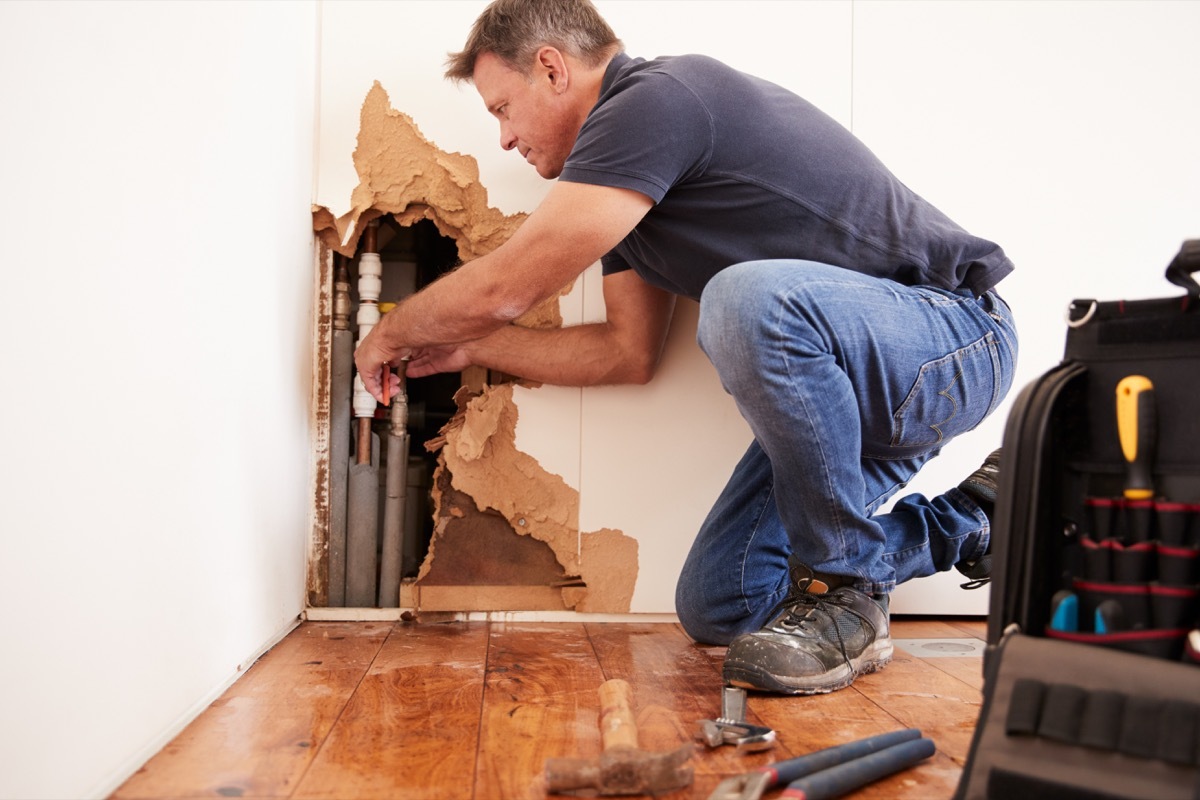 older man repairing damaged wall