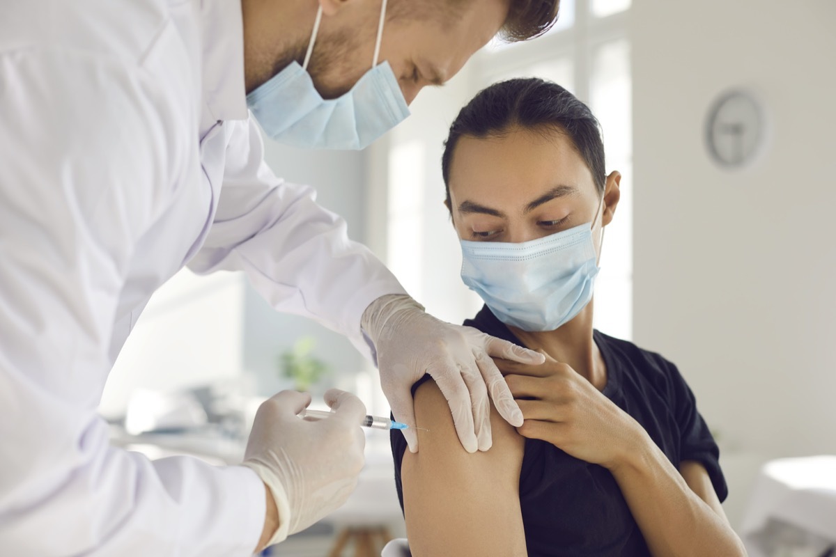 man patient in protective mask looking at doctor man medical worker making vaccination injection in arm from coronavirus disease