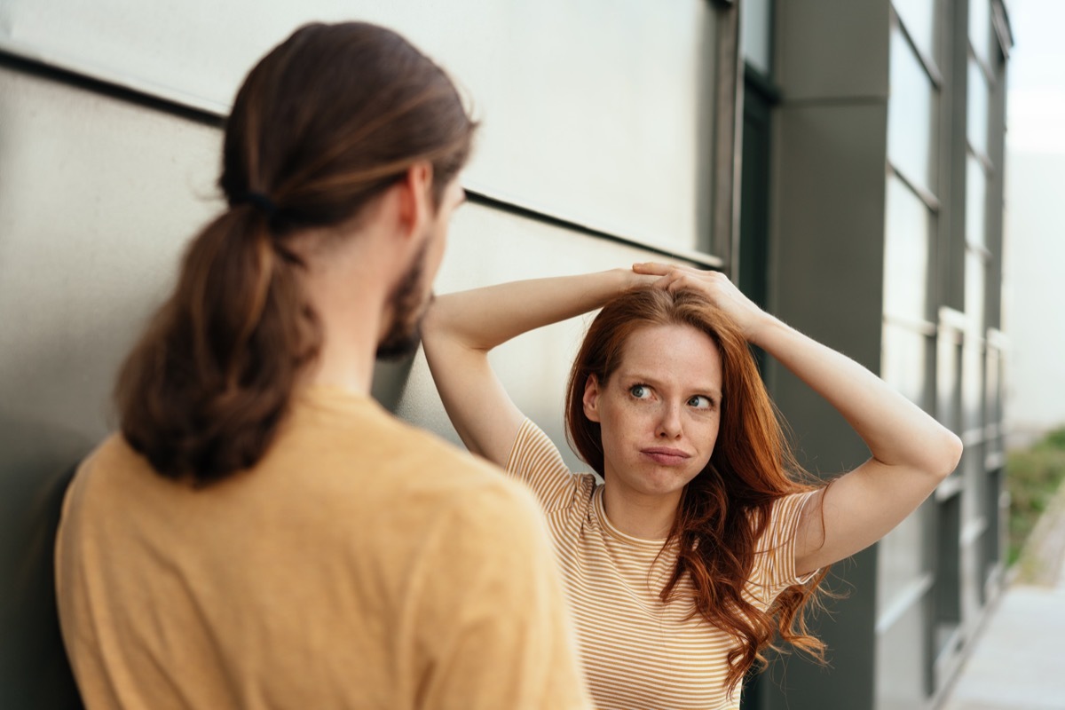 Young woman looking at her boyfriend in disbelief puffing out her cheeks with a sideways glance as they chat